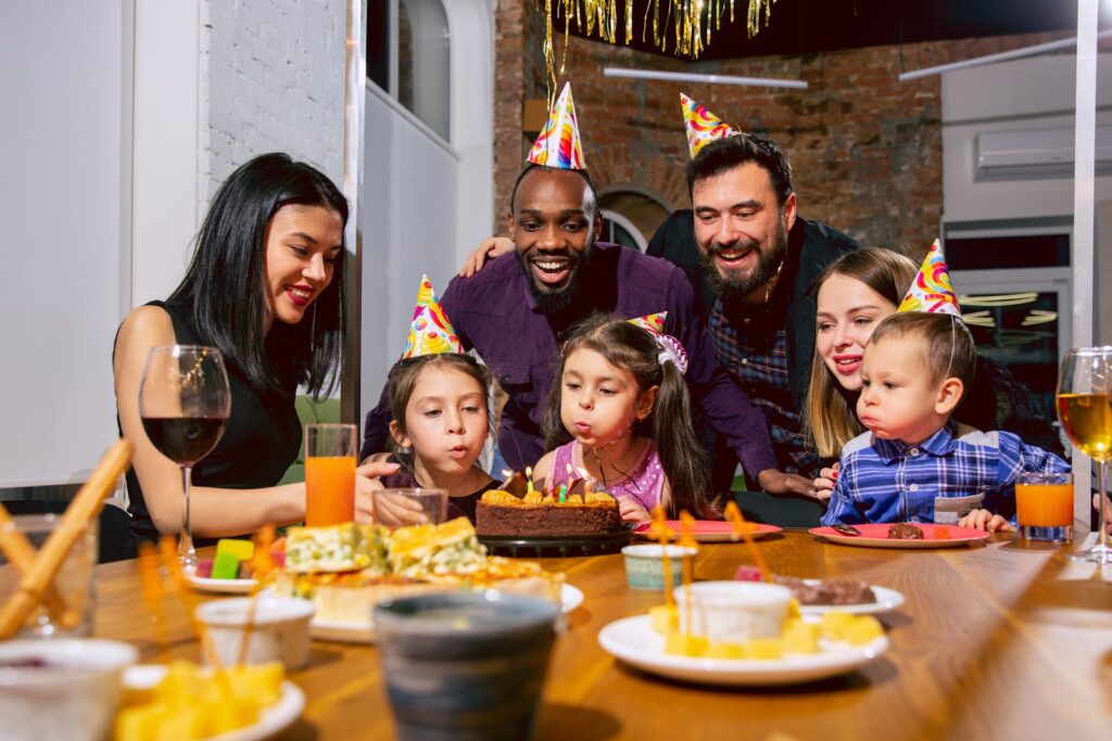 Happy family gets together to celebrate a birthday at home while eating a birthday cake.