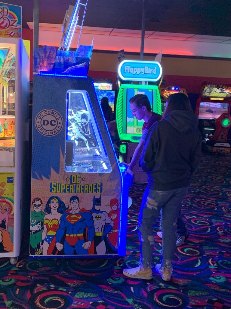 A couple plays an arcade game together while on a date.