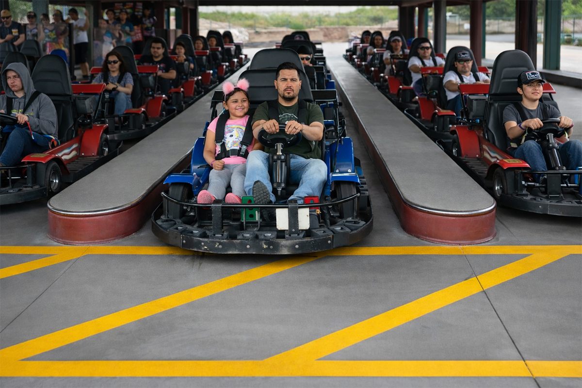 Indoor go-kart track with racers driving toward the camera